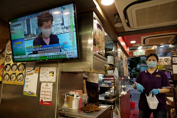 A restaurant employee prepares a takeaway meal while a TV screen shows Hong Kong Chief Executive Carrie Lam during a news conference in Hong Kong on July 31, 2020. 