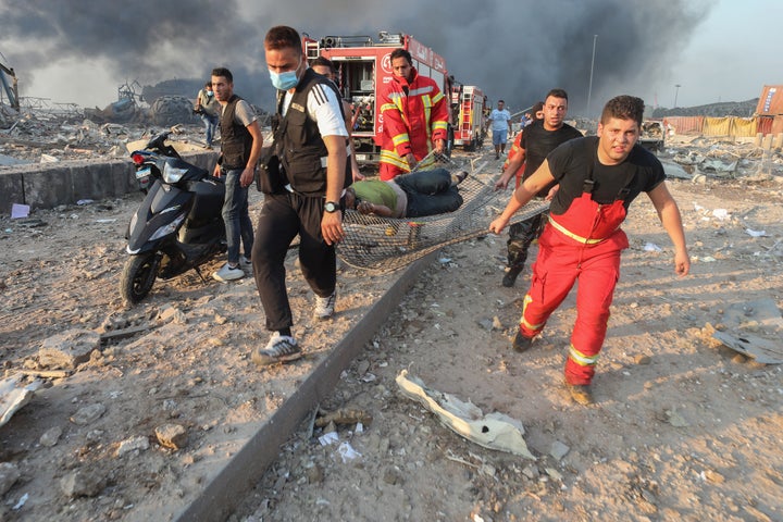 Firefighters carry an injured person from the scene of the explosion. 