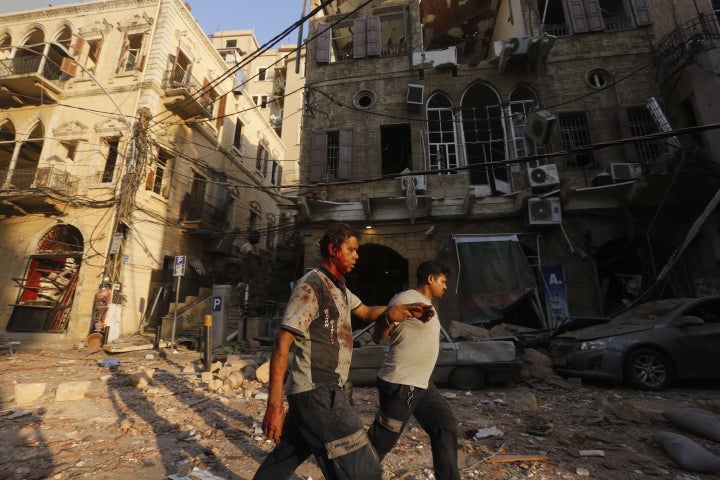 A wounded man is helped as he walks through debris in Beirut's Gemmayzeh district Tuesday. 