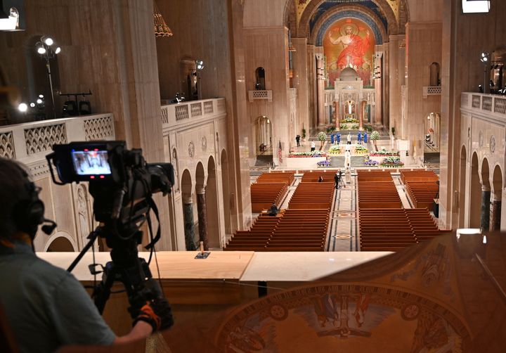 A cameraman films members of the clergy arriving for an online Easter Sunday Mass in front of empty pews at the Basilica of t