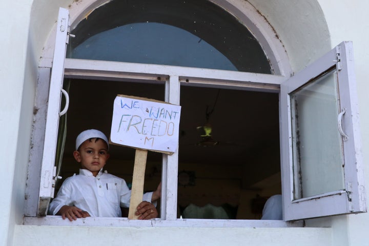 A boy holds a placard during a protest on the outskirts of Srinagar on August 3, 2020, a year after Indian authorities abrogated Article 370. 