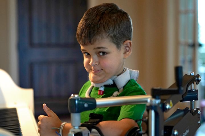 Braden Scott, who was diagnosed with AFM in 2016 and was almost completely paralyzed, gives a thumbs-up as he pauses while practicing on the piano in Tomball, Texas, in March 2019.