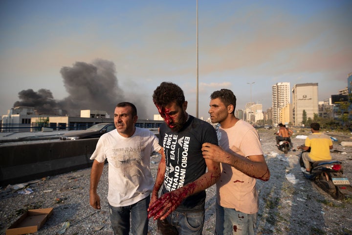 People help a man who was wounded in a massive explosion in Beirut, Lebanon, Tuesday, Aug. 4, 2020. (AP Photo/Hassan Ammar)