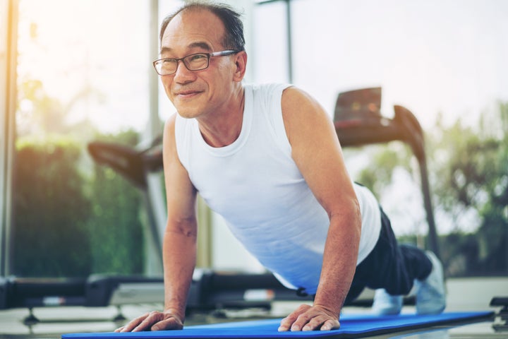 Senior man push up in fitness gym. Mature healthy lifestyle.