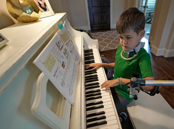 Braden Scott uses a device to support his left arm as he practices on the piano.