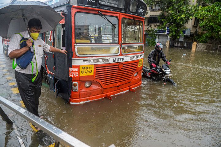 Commuters make their way through a flooded road in Mumbai on August 4, 2020. 
