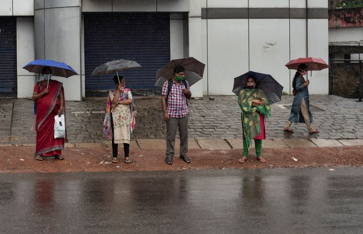 People stand holding umbrellas during monsoon rains amid the coronavirus pandemic in Kochi, June 6, 2020. 