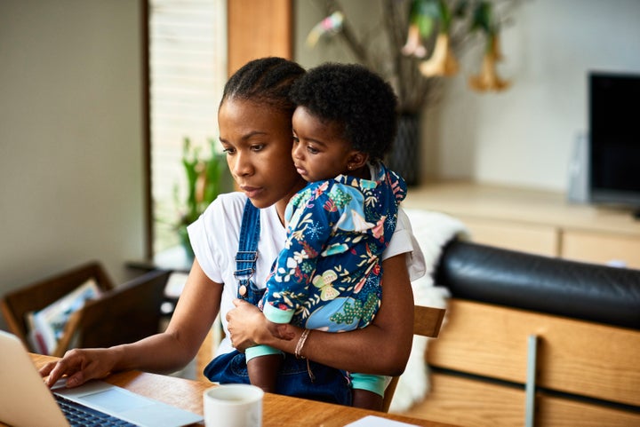 Woman with baby son (6-11 months) working on laptop at home