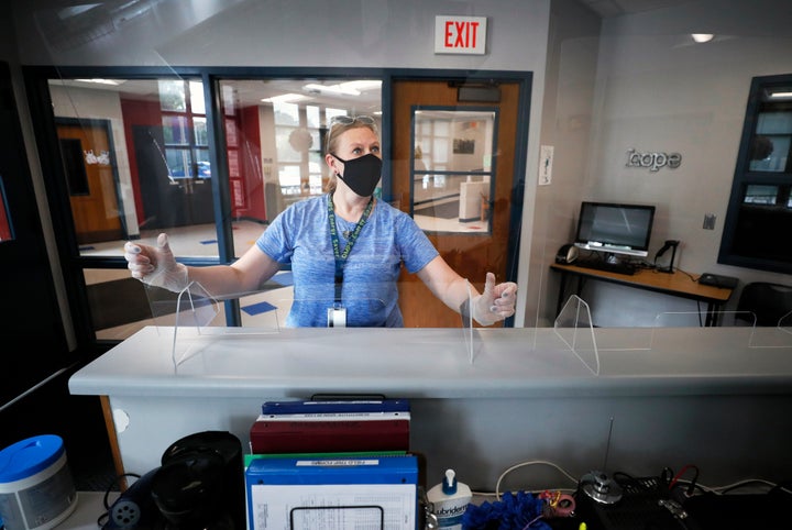 Des Moines Public Schools employee Sarah Holland installs a plexiglass shield in the office at Oak Park Elementary School on July 30, 2020, in Des Moines, Iowa.