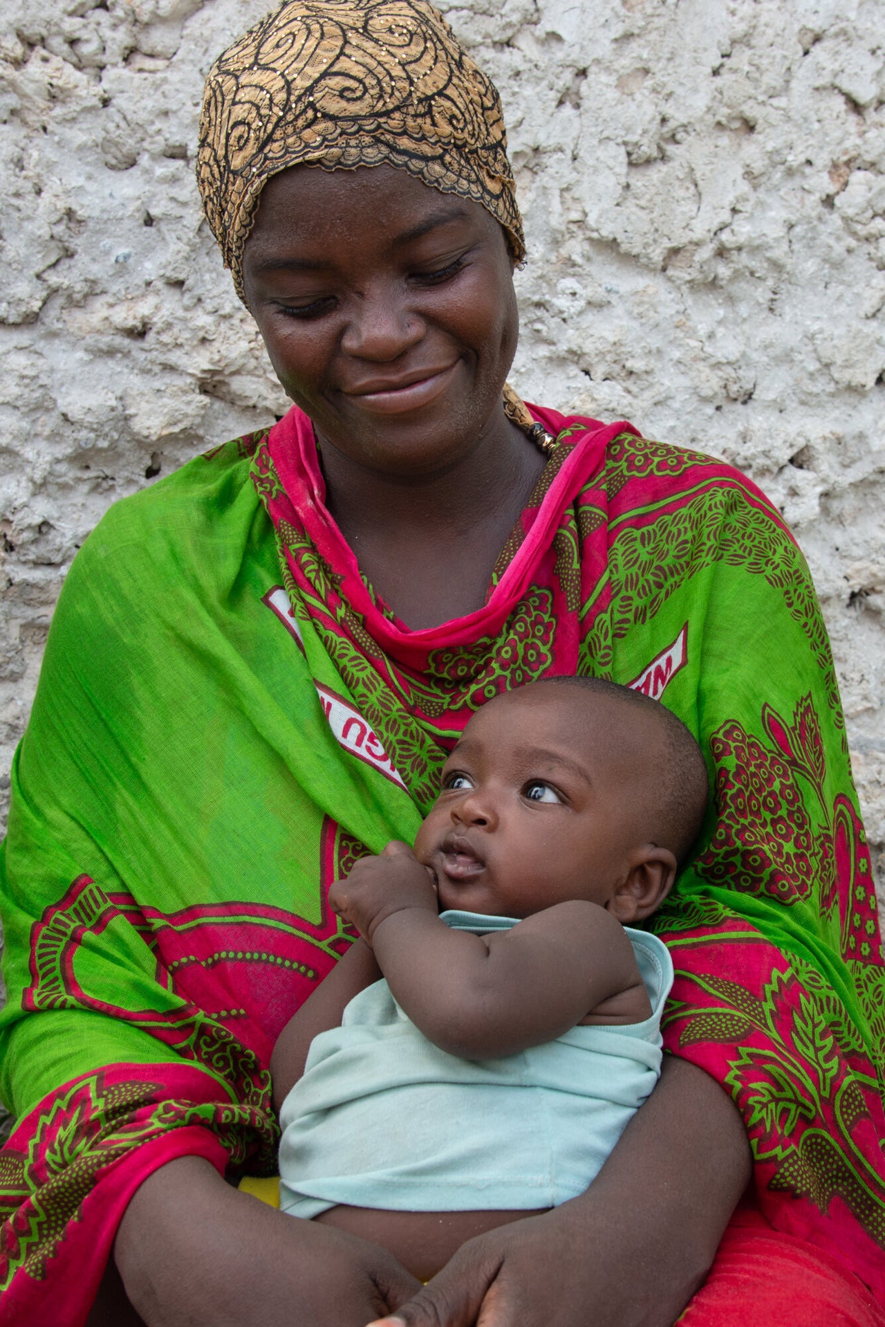 Zedi Abdallah Abdallah sits outside her house with her son. She has been a sponge farmer for two years. She says that sponge farming has better allowed her to provide for her children and her basic needs. Otherwise, she says, there is no work.