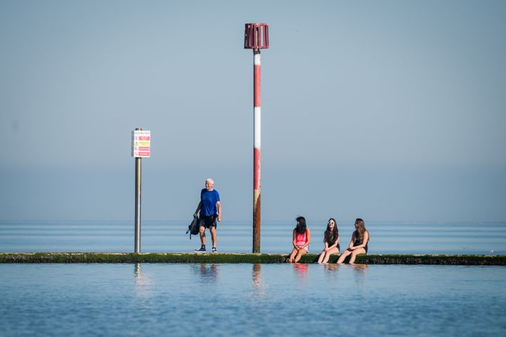 A man talks to three girls as they dip their feet in the saltwater lido on Friday in Margate