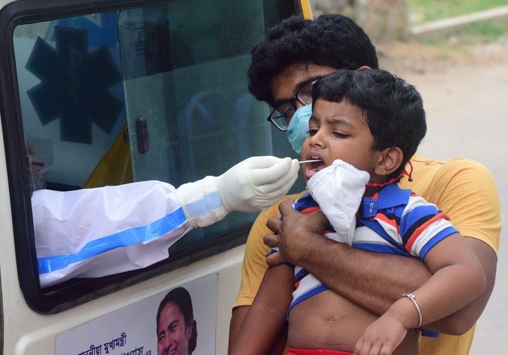 Officials of the Kolkata Municipal Corporation health department conduct a test on a boy in Kolkata on August 7, 2020.