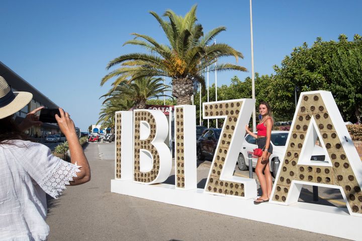 Una turista posa en un letrero de Ibiza