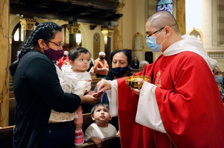 Parishioners receive the sacrament from the Rev. Luis Gabriel Medina during Communion at Saint Bartholomew Roman Catholic Church in the Queens borough of New York, July 6.