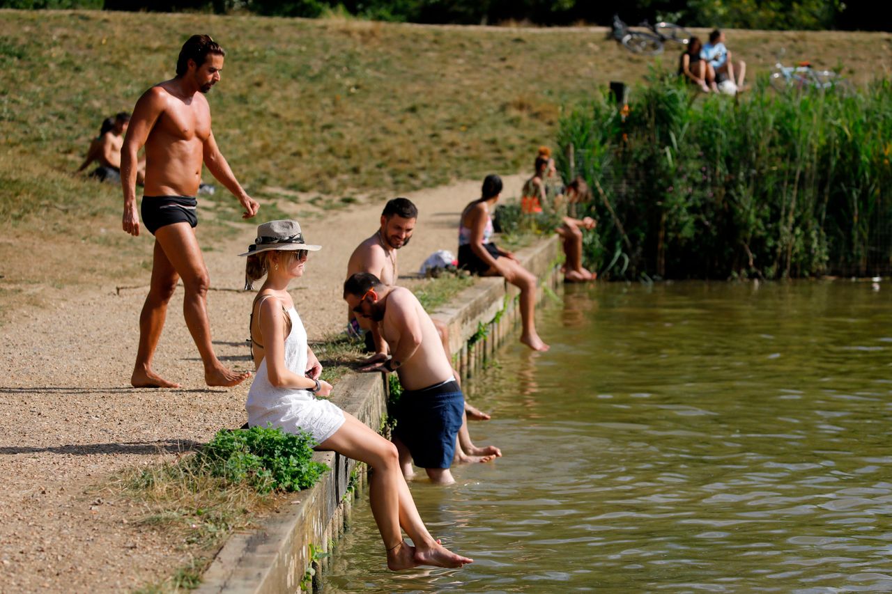 People sunbathe by Hampstead Heath ponds as the temperature soars in London.