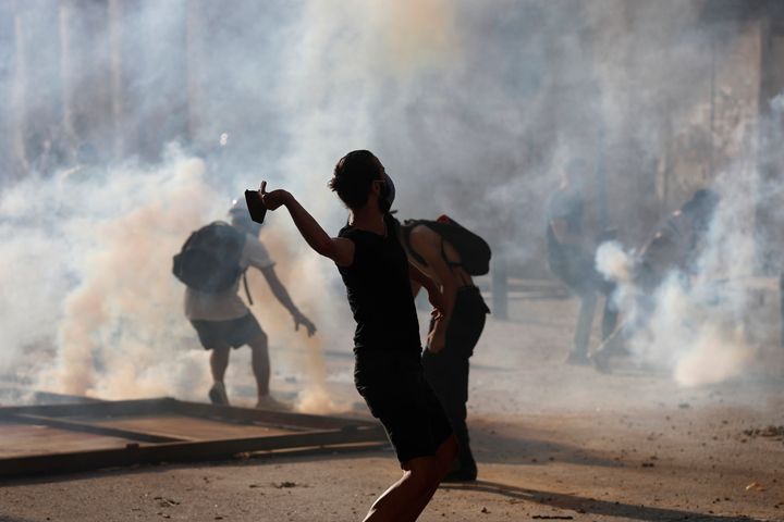 Anti-government protesters are covered by the smoke of tear gas, as they clash with riot police, during a protest against the political elites and the government, in Beirut, Lebanon, Saturday, Aug. 8, 2020. 