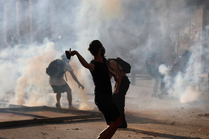 Anti-government protesters are covered by the smoke of tear gas, as they clash with riot police, during a protest against the