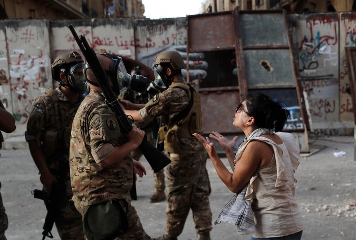 An anti-government protester, reacts in front of Lebanese soldiers during a protest against the political elites and the gove