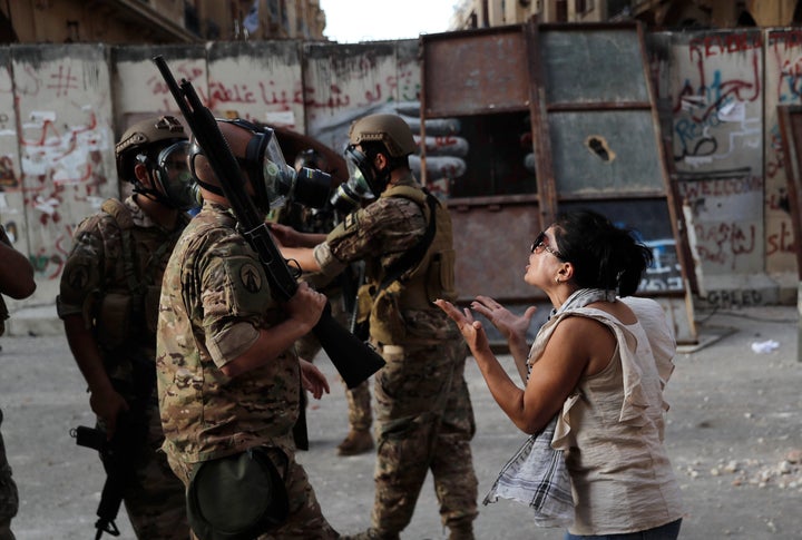 An anti-government protester, reacts in front of Lebanese soldiers during a protest against the political elites and the government, in Beirut, Lebanon, Saturday, Aug. 8, 2020.