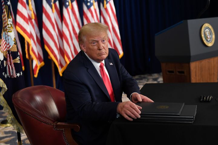 President Donald Trump prepares to sign four executive orders during a news conference at the Trump National Golf Club in Bedminster, N.J., Saturday, Aug. 8, 2020. Seizing the power of his podium and his pen, Trump on Saturday moved to bypass the nation's elected lawmakers as he claimed the authority to defer payroll taxes and extend an expired unemployment benefit after negotiations with Congress on a new coronavirus rescue package collapsed. (AP Photo/Susan Walsh)