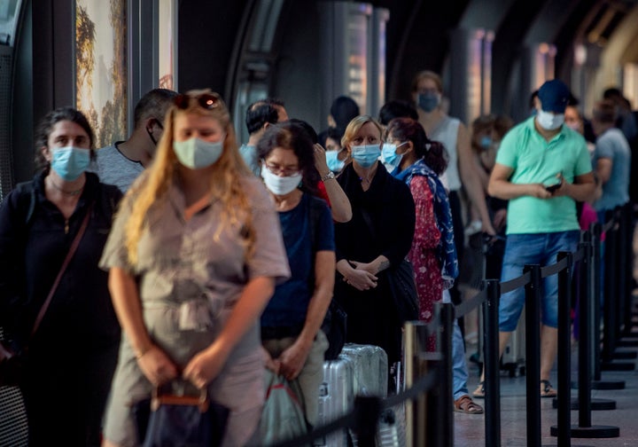 Passengers queue at a Corona test center at the airport in Frankfurt, Germany, Friday, Aug. 7, 2020. (AP Photo/Michael Probst)