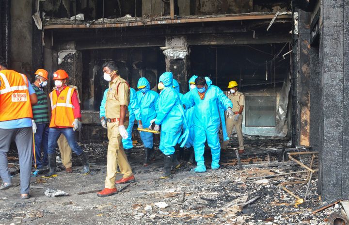 Rescuers in protective suits carry the body of a victim from Hotel Swarna Palace where a fire broke out early morning in Vijayawada, Andhra Pradesh state, India, Sunday, Aug. 9, 2020. (AP Photo)