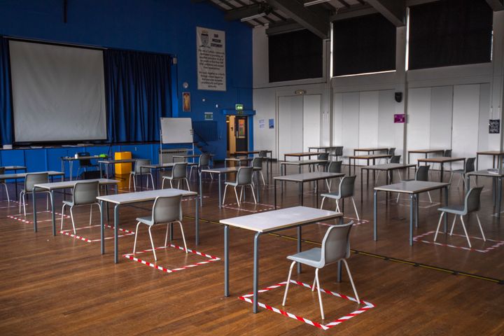 Socially distanced desks are set out for lesson in the hall at a school in Dukinfield, England.