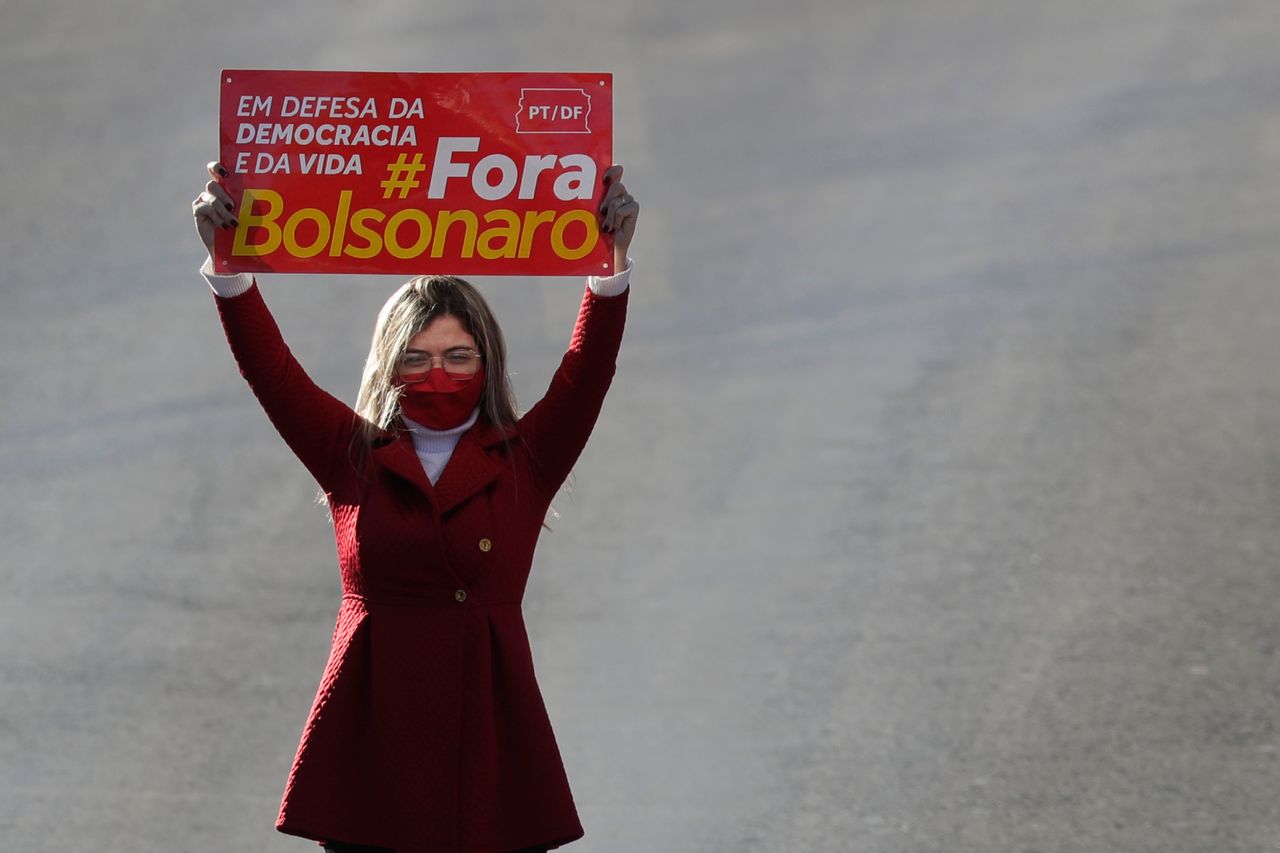 A demonstrator holds a sign that reads "In defense of life and democracy. Get out Bolsonaro" during a protest last week, as Brazil passed 100,000 coronavirus deaths.