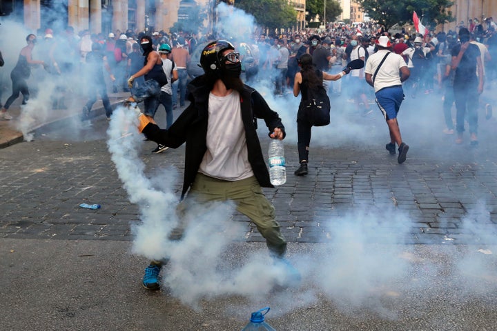 Protesters throw back tear gas canisters towards riot policemen during an anti-government protest.