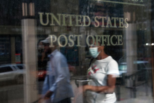 Customers walk into a Brooklyn post office last week in New York City. The U.S. Postal Service is under...