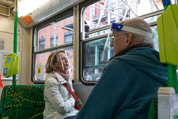 Two commuters wearing face shields are seen as they travel by tram during lockdown in Melbourne, Australia, Wednesday, Aug. 5, 2020. (AP Photo/Asanka Brendon Ratnayake)