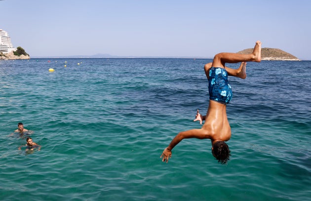 A boy jumps into the sea from the rocks of Magaluf beach on July 30 in Mallorca, Spain. The area is a...