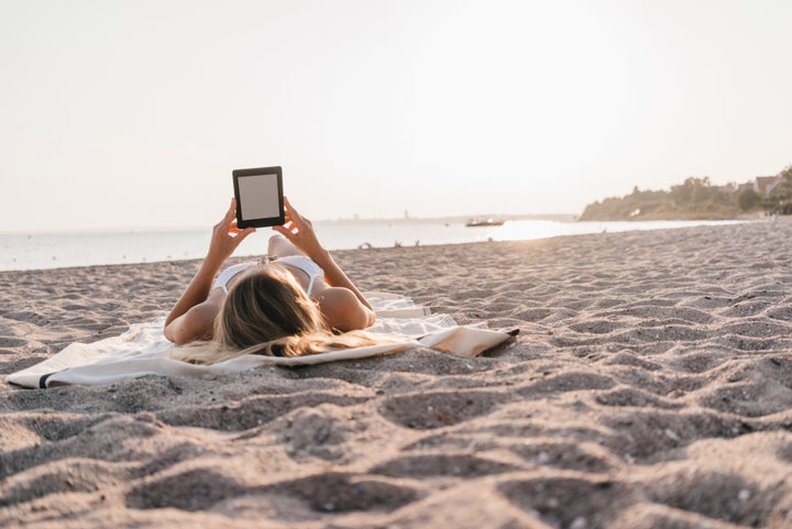 Una mujer lee en su Kindle en la playa.