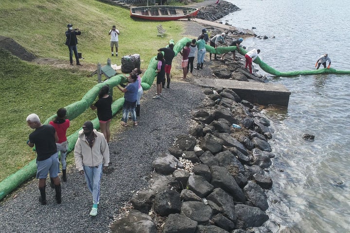 Volunteers carry the handmade oil barrier to block leaked oil from the MV Wakashio bulk carrier.