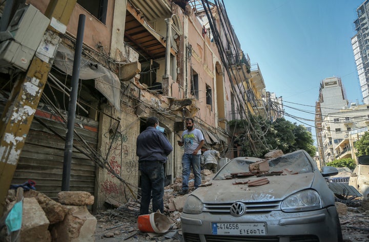 People inspect destruction outside a damaged building the day after the massive explosion.