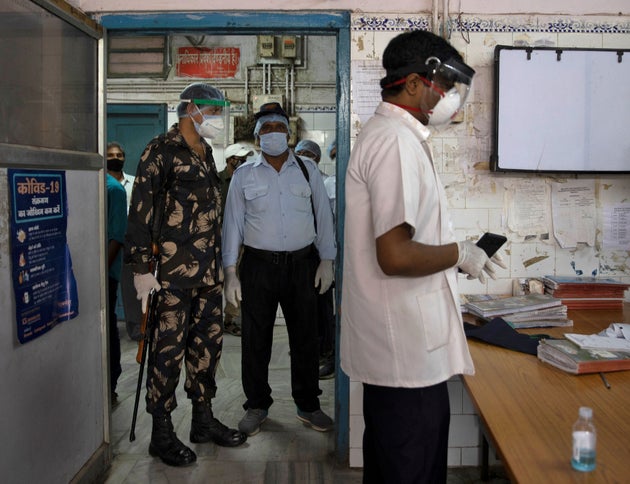 Armed security personnel stand guard as Dr. Kumar Gaurav speaks to his colleagues on the emergency ward...