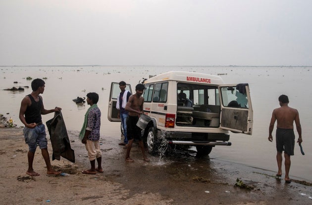 People wash an ambulance on the banks of River Ganga behind Jawahar Lal Nehru Medical College and Hospital,...