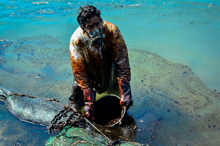 油まみれになりながらバケツですくう男性 8月8日撮影 (Photo by JEAN AURELIO PRUDENCE/L'Express Maurice/AFP via Getty Images)