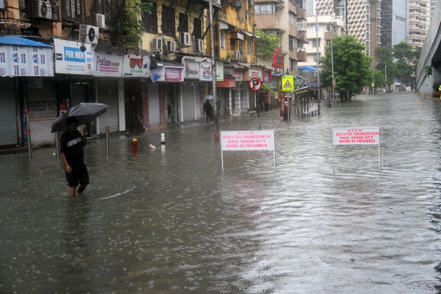 MUMBAI, INDIA - AUGUST 4: People make their way through a flooded road due to heavy monsoon rain in Mumbai,...