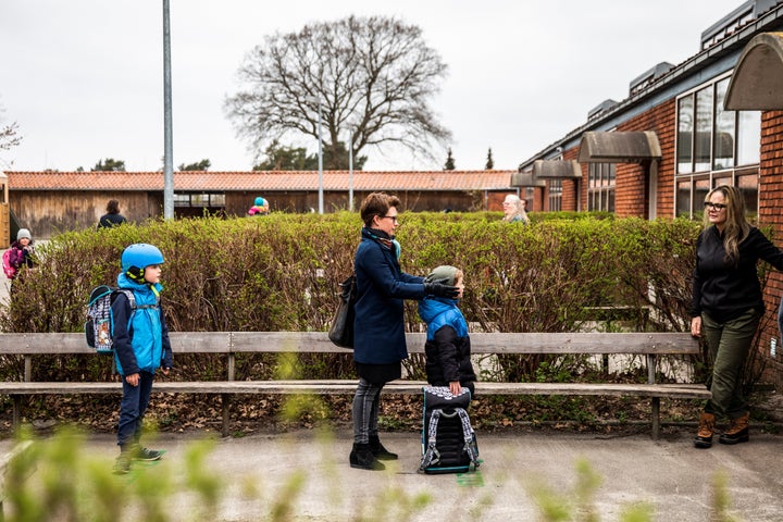 Parents with their children stand in a socially-distanced queue waiting to enter a school in Copenhagen, Denmark, April 15, 2020.