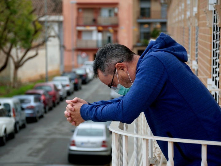 Un hombre con mascarilla en el balcón de su casa.