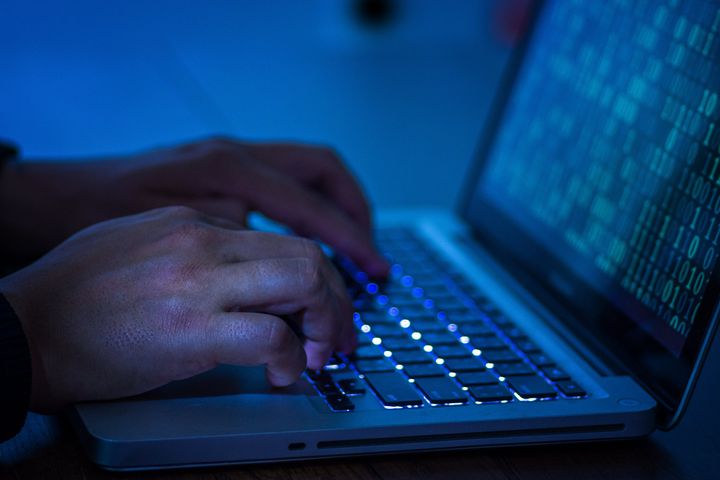 A computer programmer or hacker prints a code on a laptop keyboard to break into a secret oganization system.
