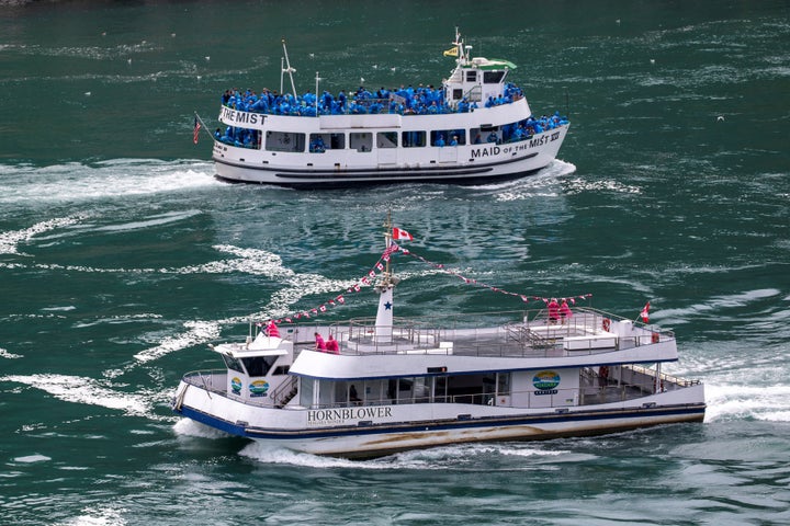 American tourist boat Maid Of The Mist, limited to 50 per cent occupancy under New York state's rules amid the spread of the coronavirus disease (COVID-19), glides past a Canadian vessel limited under Ontario's rules to just six passengers, in Niagara Falls, Ont. on July 21, 2020.