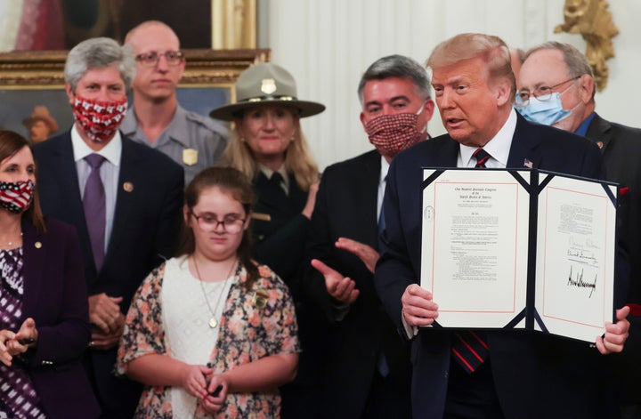 President Donald Trump holds up the Great American Outdoors Act after signing it Aug. 4. 