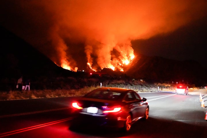Motorists make their way along a road as the Ranch Fire burns, Thursday, Aug. 13, 2020, in Azusa, California. Heat wave condi