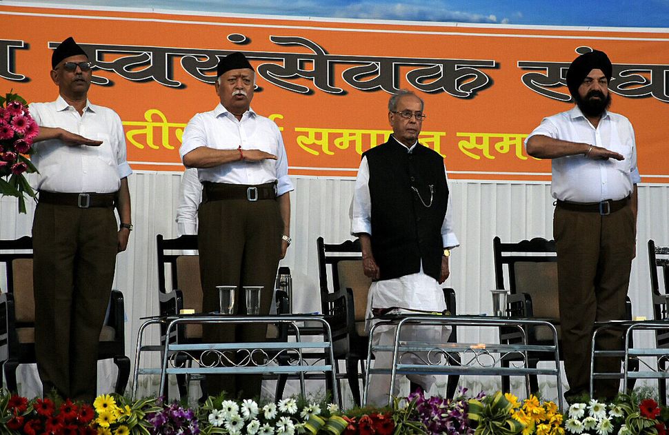 Mohan Bhagwat, chief of the Hindu nationalist organisation Rashtriya Swayamsevak Sangh (RSS), takes an oath with other members as former Indian President Pranab Mukherjee stands beside them during an event at the RSS headquarters in Nagpur on June 7, 2018. 