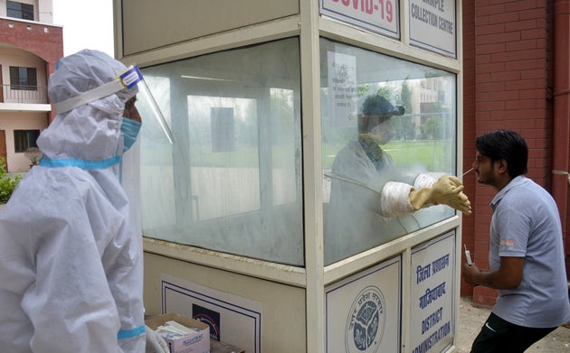 GHAZIABAD, INDIA - AUGUST 12: A medic in a kiosk collects swab samples for Covid-19 testing at IMS College,...