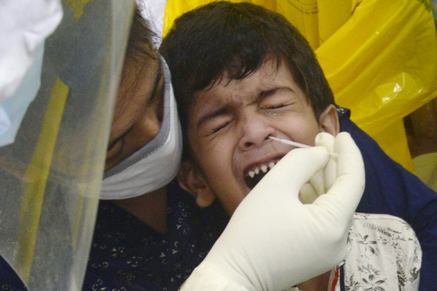 KOLKATA, WEST BENGAL, INDIA - 2020/08/08: Health worker collects swab sample from a child for antigen...