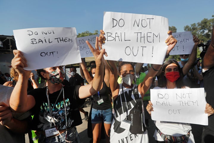 NGO volunteers hold up placards against Lebanese politicians, as they protest during the visit of U.S. Undersecretary of State for Political Affairs David Hale to the main gathering point for volunteers, near the site of last week's explosion that hit the seaport of Beirut, Lebanon, Thursday, Aug. 13, 2020. (AP Photo/Hussein Malla, Pool)