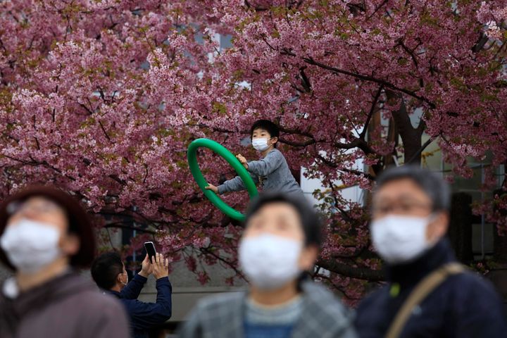People with masks visit a cherry blossom festival in Matsuda, Kanagawa prefecture, south of Tokyo, Saturday, Feb. 29, 2020. The coronavirus outbreak began to look more like a worldwide economic crisis as anxiety about the infection emptied shops and amusement parks, canceled events, cut trade and travel and dragged already slumping financial markets even lower. (AP Photo/Jae C. Hong)